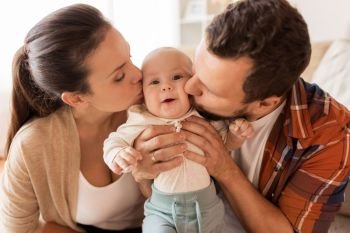family, parenthood and people concept - happy mother and father kissing little baby at home. happy mother and father kissing baby at home