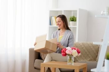 delivery, mail and people concept - smiling middle-aged woman opening parcel box at home. smiling woman opening parcel box at home