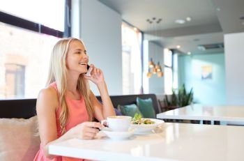 food, people and leisure concept - happy woman drinking coffee at restaurant and calling on smartphone. woman with coffee calling smartphone at restaurant
