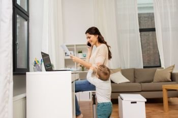 motherhood, multi-tasking, family and technology concept - happy working mother with baby, papers and laptop calling on smartphone at home. happy mother with baby and papers working at home
