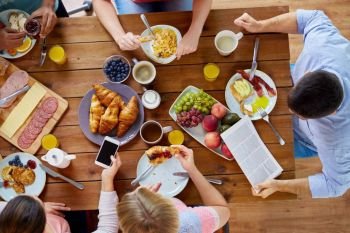 breakfast, technology and family concept - group of people with smartphones eating and photographing food at table. people with smartphones eating food at table