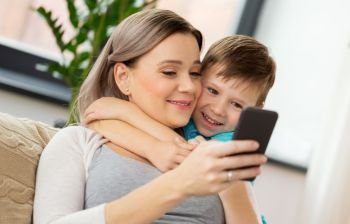 family, technology and people concept - happy mother and little son with smartphone at home. happy family with smartphone at home