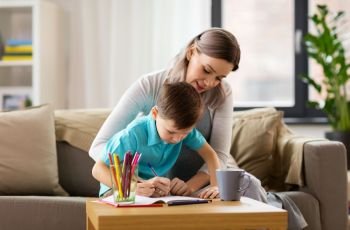 family and education concept - happy mother and little son with workbook writing or drawing at home. mother and son with workbook at home