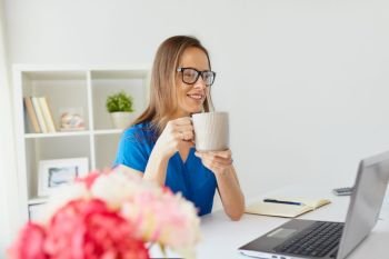 business, freelance, people and technology concept - happy smiling woman with laptop computer drinking coffee at home or office. woman with laptop and coffee at home or office
