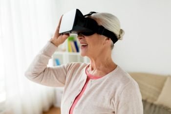 technology, augmented reality, entertainment and people concept - senior woman with virtual headset or 3d glasses playing videogame at home. old woman in virtual reality headset or 3d glasses