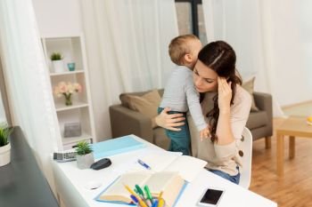 multi-tasking, education, motherhood and family concept - tired mother student with baby learning at home. mother student with baby learning at home