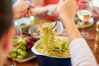food, culinary and eating concept - hands taking pasta with basil from bowl on table. pasta with basil in bowl and other food on table