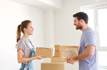 mortgage, people and real estate concept - happy couple with boxes moving to new home. happy couple with boxes moving to new home
