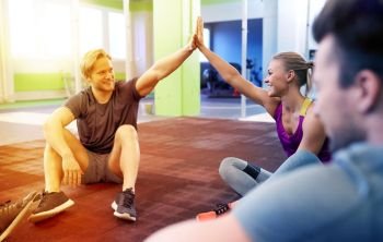 fitness, sport, exercising, gesture and healthy lifestyle concept - group of happy people resting and making high five in gym. group of happy friends making high five in gym