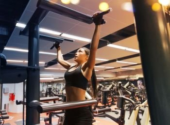 sport, fitness, lifestyle and people concept - woman exercising and doing pull-ups in gym. woman exercising and doing pull-ups in gym