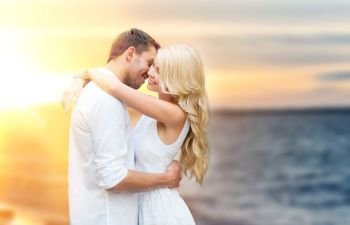 love, summer holidays, relationships and people concept - happy couple hugging over sea background. happy couple hugging and kissing on summer beach