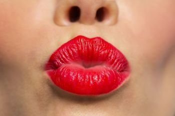 beauty, make up and mouth expression concept - close up of woman lips with red lipstick making kissing or duck face. woman lips with red lipstick making kiss 