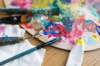 fine art, creativity and artistic tools concept - close up of palette knife or painting spatula, brushes and paint tube. palette knife or spatula, brushes and paint tube