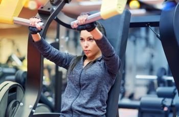 fitness, sport, bodybuilding, exercising and people concept - young woman flexing muscles on seated chest press machine in gym. woman flexing muscles on chest press gym machine 