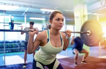 fitness, sport, training, exercising and lifestyle concept - group of people with barbells doing squats in gym. group of people training with barbells in gym