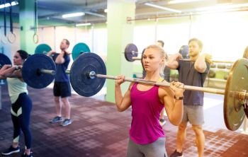 fitness, sport, training, exercising and lifestyle concept - group of people with barbells doing shoulder press in gym. group of people training with barbells in gym