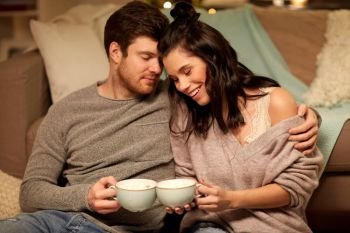 hygge, leisure and people concept - happy couple drinking cacao with marshmallow at home. happy couple drinking cacao at home