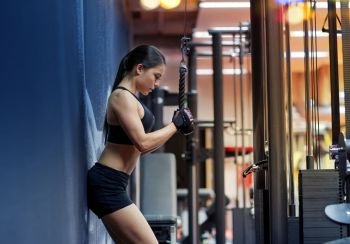 sport, fitness, bodybuilding, lifestyle and people concept - woman flexing arm muscles on cable machine in gym. woman flexing arm muscles on cable machine in gym