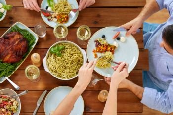 food, thanksgiving day, eating and leisure concept - people with pasta having dinner. people at table with food eating pasta for dinner