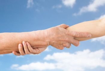 people, age and charity concept - close up of senior and young woman holding hands over blue sky and clouds background. close up of senior and young woman holding hands