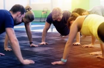fitness, sport, exercising, training and healthy lifestyle concept - group of people doing straight arm plank in gym. group of people exercising in gym