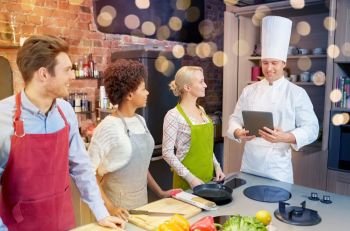 cooking class, culinary, food, technology and people concept - happy friends with tablet pc in kitchen. happy friends with tablet pc in kitchen