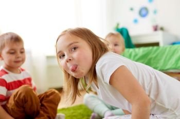 childhood, leisure and facial expressions concept - girl showing tongue at home. girl showing tongue at home