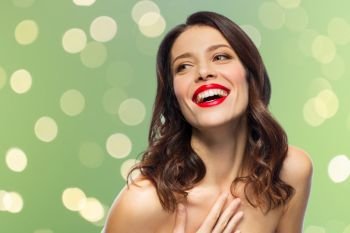 beauty, make up and people concept - happy laughing young woman with red lipstick over green background with lights. beautiful laughing young woman with red lipstick