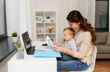 motherhood, multi-tasking, family and people concept - happy mother or female web designer with baby, documents and laptop working at home. mother with baby and documents working at home