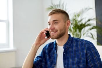 business, technology and communication concept - smiling young man calling on smartphone at office. smiling young man calling on smartphone at office