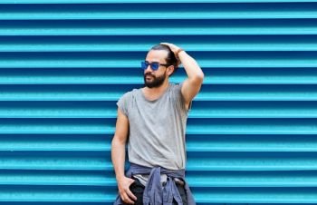 fashion, style and people concept - man in sunglasses with beard posing over ribbed blue wall background. man in sunglasses posing over ribbed blue wall