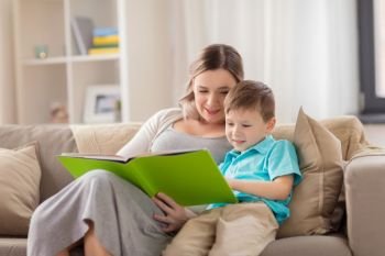 people and family concept - happy mother and little son reading book on sofa at home. happy family reading book at home
