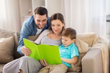 people and family concept - happy mother, father and little son reading book on sofa at home. happy family reading book at home