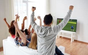 football, leisure and people concept - happy friends with drinks watching soccer game on tv at home and celebrating victory. friends watching soccer on tv and celebrating goal
