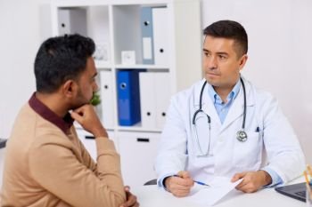 medicine, healthcare and people concept - doctor showing prescription to male patient at clinic. doctor showing prescription to patient at clinic