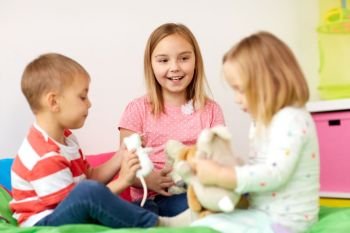childhood, leisure and people concept - happy kids playing with plush toys at home. happy kids playing with plush toys at home