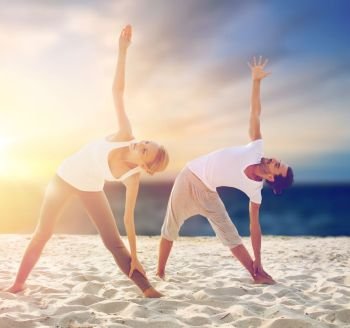 fitness, sport and people concept - couple making yoga exercises on beach. couple making yoga exercises on beach