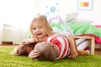 childhood, leisure and family concept - happy little kids lying on floor or carpet. happy little kids lying on floor or carpet