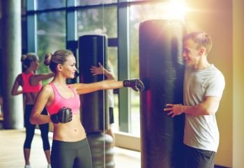 sport, fitness, lifestyle and people concept - smiling woman with personal trainer boxing in gym. smiling woman with personal trainer boxing in gym