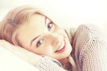 rest, relax and people concept - smiling young woman or teen girl lying on pillow at home. young woman or teen girl lying on pillow at home