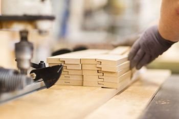 production, manufacture and woodworking industry concept - close up of worker or carpenter hand with boards at furniture factory workshop. close up of carpenter hand with boards at factory