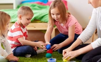 childhood, leisure and people concept - group of happy kids and and mother with modelling clay or slimes at home. kids and mother with modelling clay or slimes