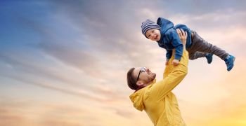 family, childhood and fatherhood concept - happy father and little son playing and having fun outdoors over evening sky background. father with son playing and having fun outdoors
