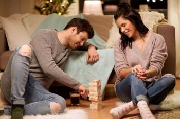 entertainment and people concept - happy couple playing block-stacking game at home. happy couple playing block-stacking game at home
