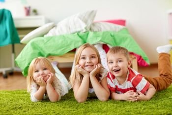 childhood, leisure and family concept - happy little kids lying on floor or carpet. happy little kids lying on floor or carpet