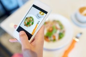 food, technology, eating and people concept - close up of woman hand with smartphone photographing salad at restaurant. hand with smartphone photographing restaurant food