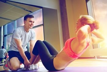 fitness, sport, training, gym and lifestyle concept - woman with personal trainer doing sit ups in gym. woman with personal trainer doing sit ups in gym