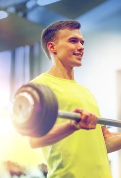 sport, fitness, lifestyle and people concept - smiling man doing exercise with barbell in gym. smiling man doing exercise with barbell in gym