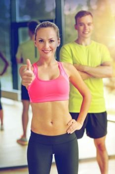sport, fitness, lifestyle and people concept - smiling man and woman showing thumbs up in gym. smiling man and woman showing thumbs up in gym