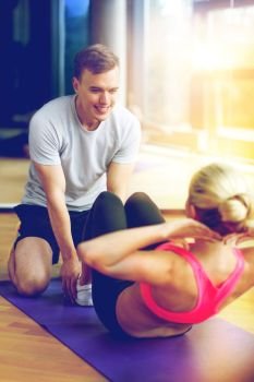 sport, fitness, lifestyle and people concept - smiling woman with male personal trainer exercising in gym. smiling woman with male trainer exercising in gym